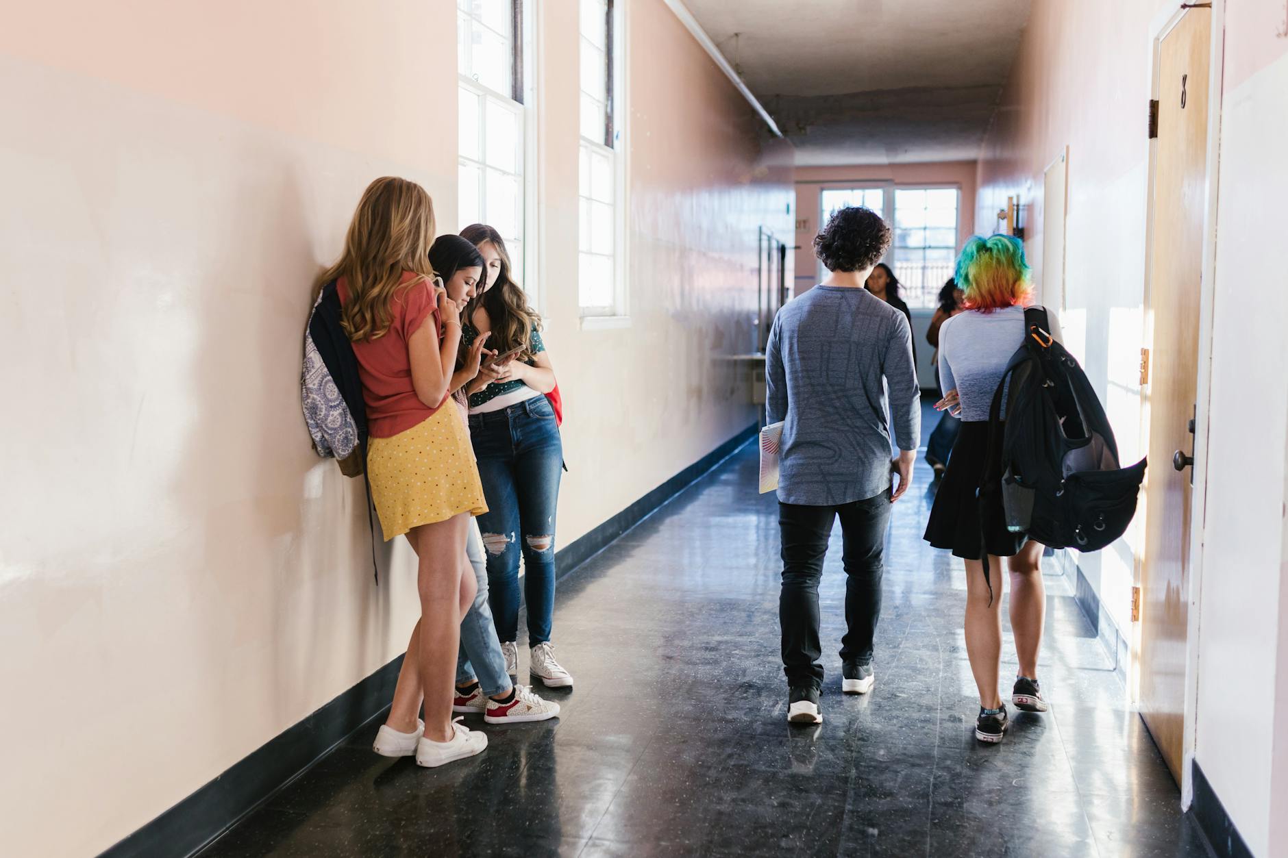 Group of teenagers interacting in a bright school hallway, showcasing diversity and everyday school life.