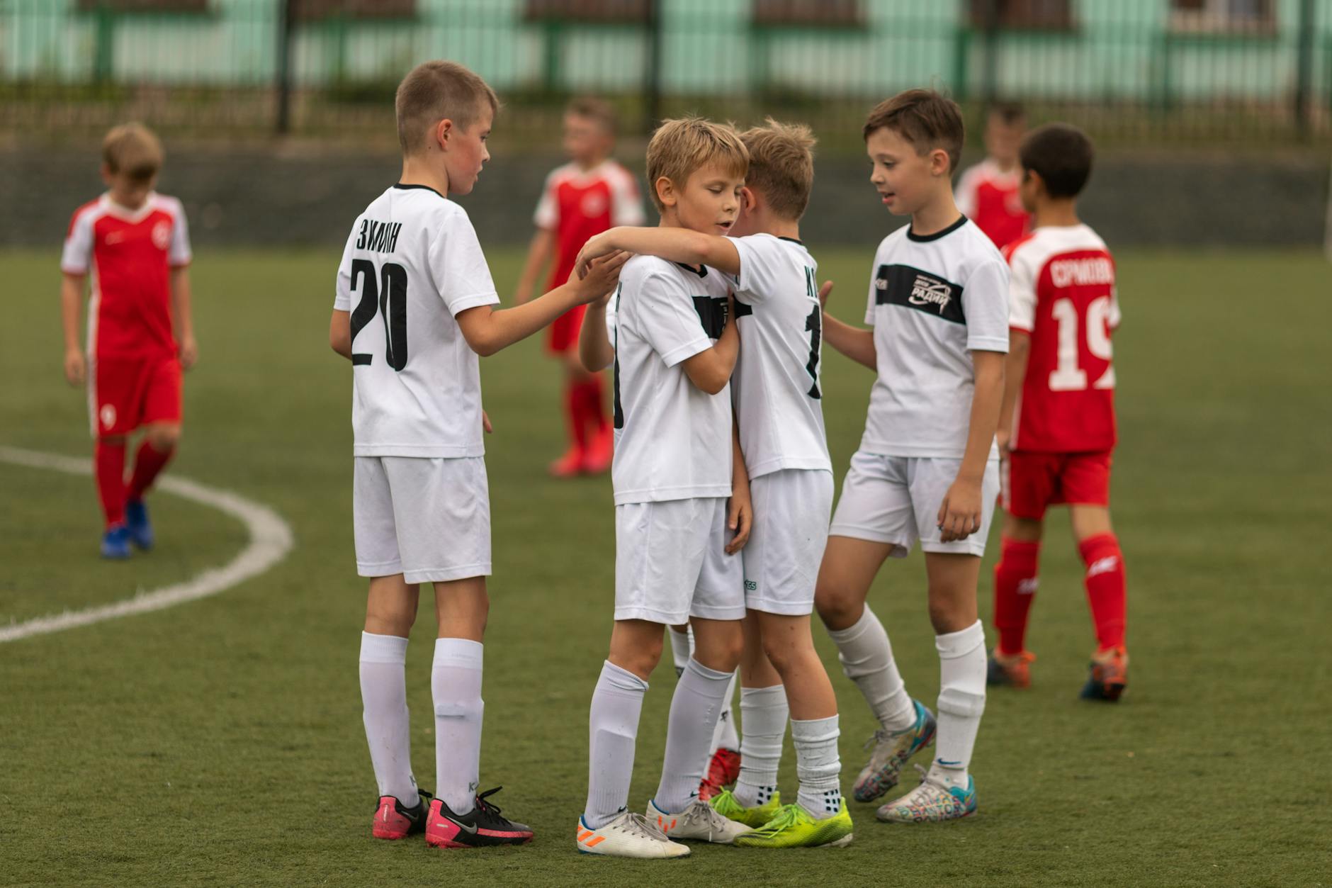 Youth soccer players huddle in sports uniforms on a grass field, fostering teamwork and unity.